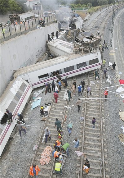 24日，救援人員在西班牙列車脫軌現(xiàn)場。一節(jié)車廂被強大的慣性拋上鐵道邊的高臺。