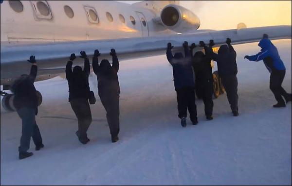 伊加爾市一架客機起飛前被凍在了跑道上。飛機上的乘客不得不下來推飛機。