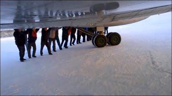 　伊加爾市一架客機起飛前被凍在了跑道上。飛機上的乘客不得不下來推飛機。
