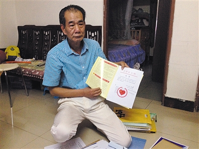 翻出一家網站贈予的“中國好人”證書，區(qū)少坤單膝跪在地上，“你看，我是中國好人啊?！?范春旭 攝