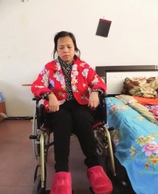 陳慶霞坐在輪椅上。她現在下身癱瘓，疾病纏身，生活不能自理。