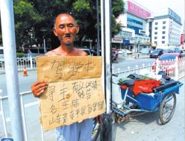 老人舉著牌子在路邊等候失主。京華時報記者譚青攝