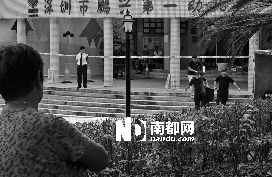 →7月19日，鵬興花園第一幼兒園門前，民警在現(xiàn)場(chǎng)進(jìn)行完勘查取證后，園長(zhǎng)和保安的尸體被運(yùn)走。南都記者 徐文閣 攝