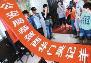 面對警方收繳的條幅，老板楊某也不好意思地用手遮擋臉