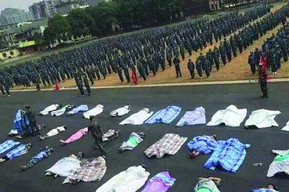 20多名女生躺在瀝青跑道上，身上嚴嚴實實地裹著棉被，接受太陽的照曬。
