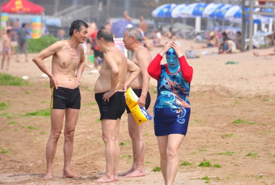 2013年7月3日，山東青島青島高溫來襲，“青島大媽”不懼滸苔，戴著“強盜面具”出現在海水浴場消暑降