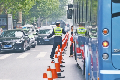 省人民醫(yī)院南門的路中間擺放反光錐，交警示意由西向東車輛從前方繞行。