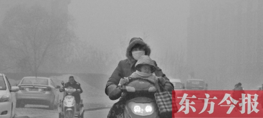 12月8日，鄭州市未來路上，一位市民帶著孩子在霧中騎行