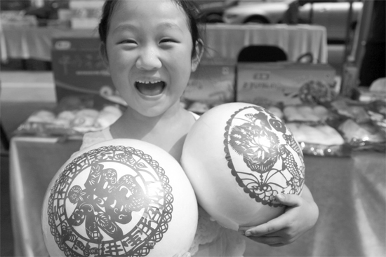 在2013河南食品安全宣傳周活動(dòng)現(xiàn)場(chǎng)，一個(gè)小女孩抱著參展的特色大饅頭樂開了花