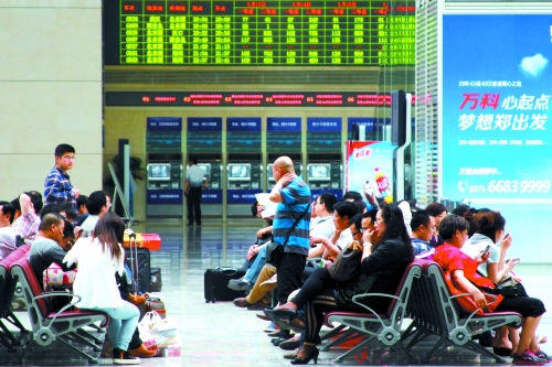 候車大廳溫度很高，一名乘客一手扇風、一手擦汗