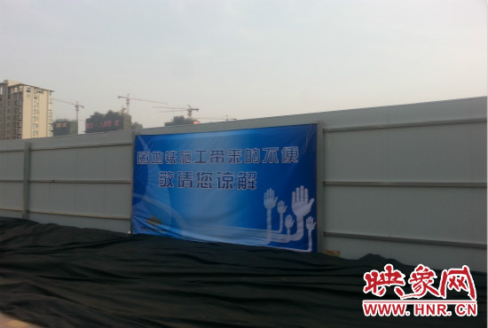 道路南側圍起了白色的圍擋，墻上標示著“因地鐵施工帶來的不便敬請您諒解”的提示牌。
