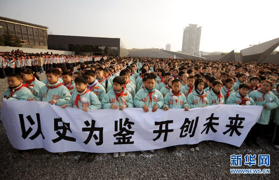 ，南京市小學生代表手持“以史為鑒 開創未來”的橫幅在南京大屠殺遇難同胞紀念館集會廣場參加悼念儀式?！? width=