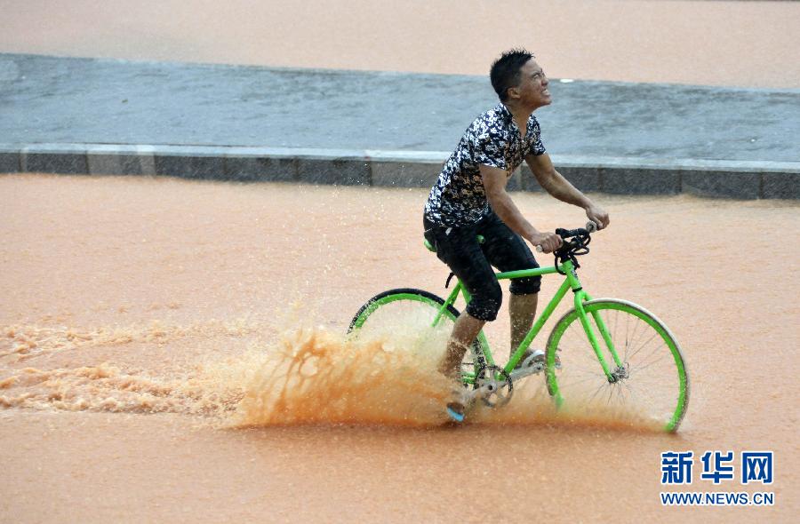 5月11日，一名行人在深圳街頭冒雨騎行。