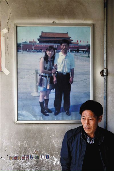 11月14日，承德市平泉縣，潘小梅父母的家，潘小梅父親靠在墻上，身后掛著數(shù)年前他和潘小梅在北京的合影照片。新京報(bào)記者