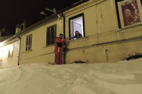 一個居民站在積雪上，可以與一名二樓鄰居在窗口握手。（來源：意大利氣象局）