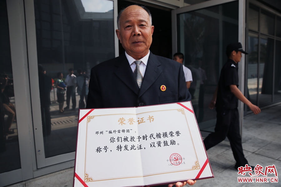 河南鄧州“編外雷鋒團”團長宋清梅向眾多記者展示中宣部授予的“時代楷模”榮譽證書。
