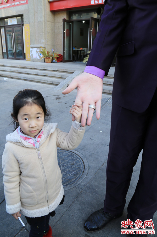 巨人“張歡”牽著一名漂亮的小女孩，兩人的手大小對(duì)比非常明顯。